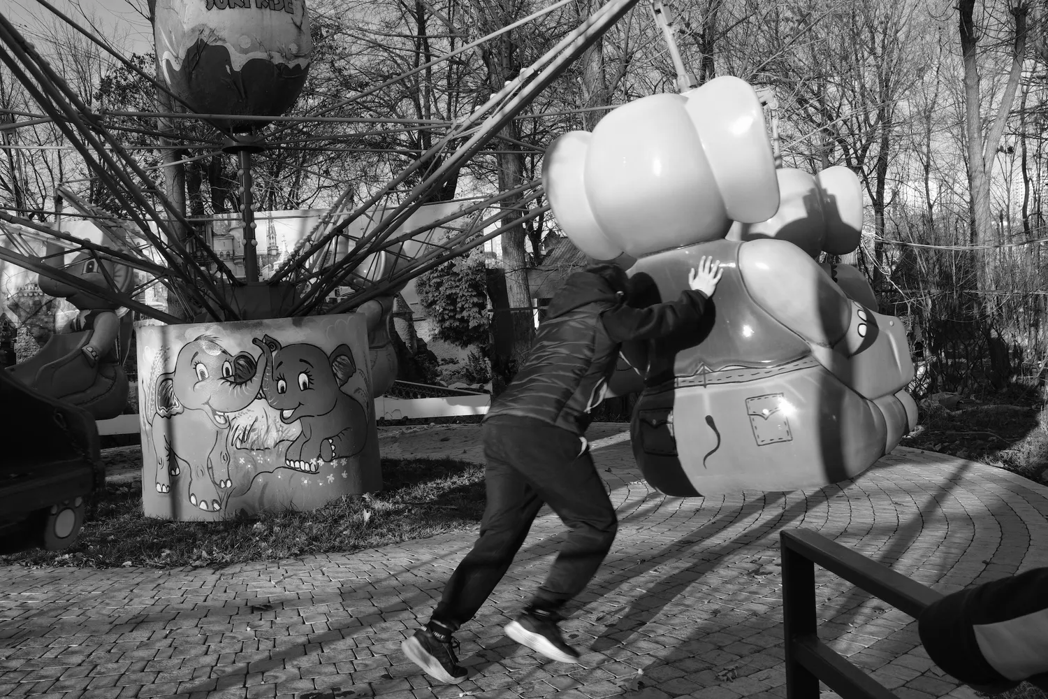 A child pushes a stopped carousel, trying to get a ride by inertia